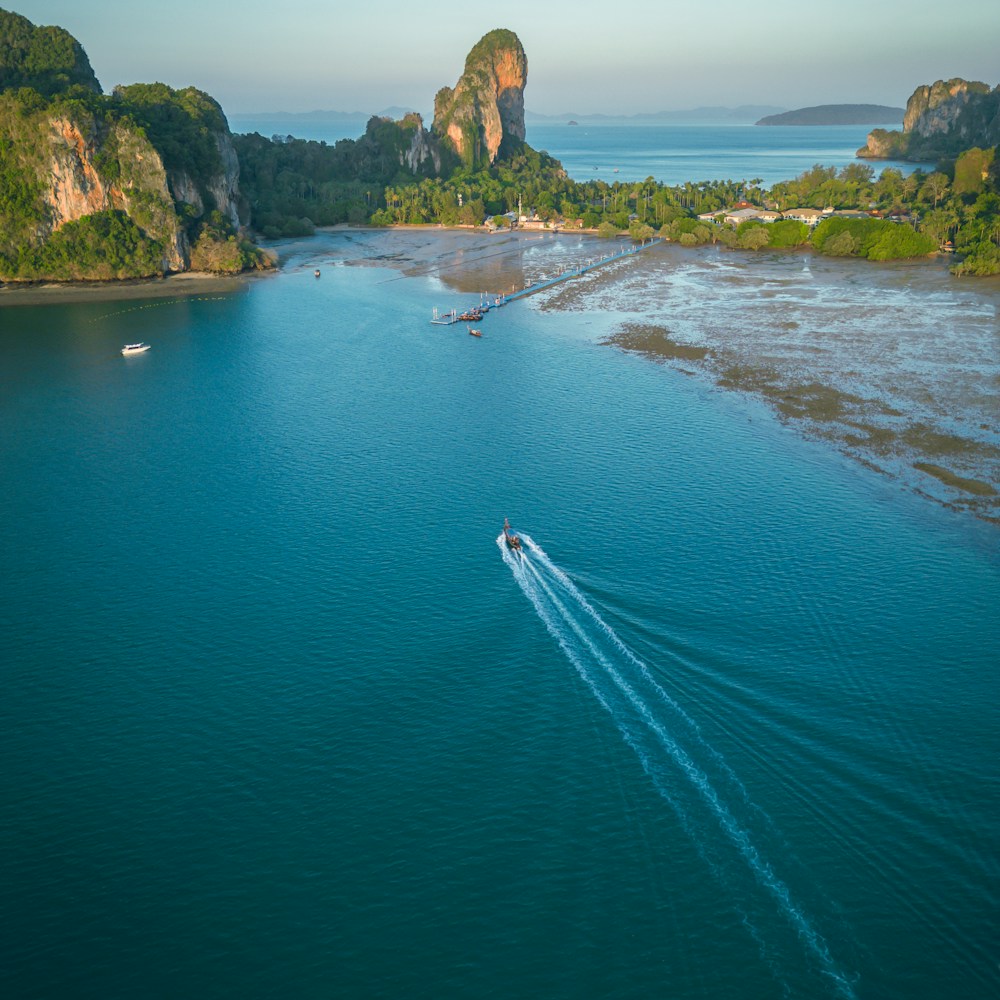A longtail boat crossing a turquoise bay past limestone cliffs