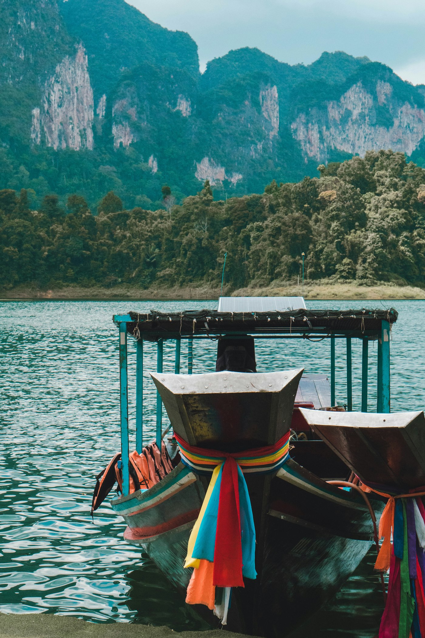 Longtail boats moored on a lake beneath limestone karst cliffs